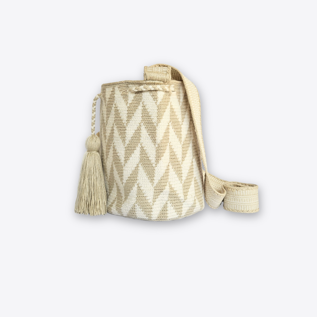 A woven bucket bag in cream and beige with a chevron pattern, featuring a matching tassel and a long shoulder strap, shown against a light gray background.