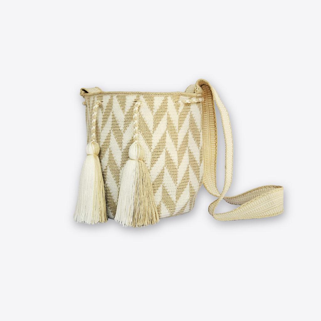 A woven bucket-style shoulder bag with a cream and tan chevron pattern, featuring two large decorative tassels on the front and a matching woven strap, shown on a light gray background.
